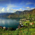 paket wisata danau toba: Panorama indah Danau Toba dengan perkampungan di tepi danau, pegunungan hijau yang menjulang, serta suasana tenang yang menjadi daya tarik utama paket wisata Danau Toba.