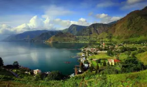paket wisata danau toba: Panorama indah Danau Toba dengan perkampungan di tepi danau, pegunungan hijau yang menjulang, serta suasana tenang yang menjadi daya tarik utama paket wisata Danau Toba.