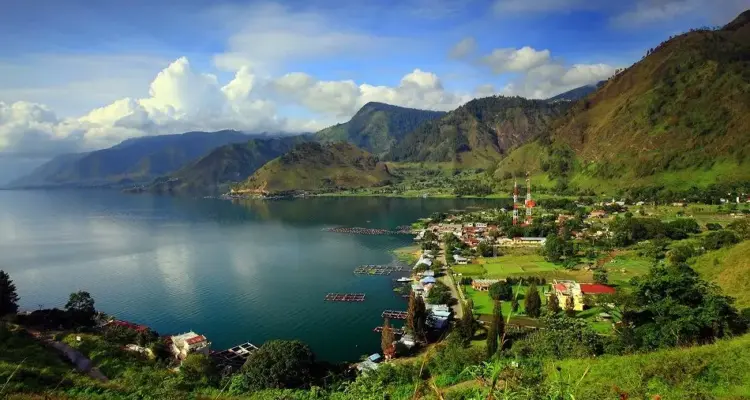 paket wisata danau toba: Panorama indah Danau Toba dengan perkampungan di tepi danau, pegunungan hijau yang menjulang, serta suasana tenang yang menjadi daya tarik utama paket wisata Danau Toba.