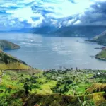 paket wisata danau toba: Panorama indah Danau Toba dari ketinggian dengan perbukitan hijau dan perkampungan di tepi danau, destinasi utama dalam paket wisata Danau Toba 3 hari 2 malam
