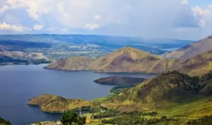 paket wisata danau toba: Pemandangan Danau Toba dengan perbukitan hijau dan pulau-pulau kecil di tengah danau, destinasi favorit untuk liburan keluarga dengan paket wisata yang praktis dan menyenangkan.