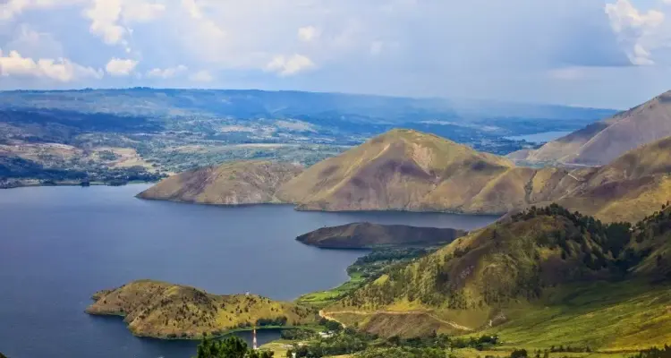 paket wisata danau toba: Pemandangan Danau Toba dengan perbukitan hijau dan pulau-pulau kecil di tengah danau, destinasi favorit untuk liburan keluarga dengan paket wisata yang praktis dan menyenangkan.