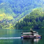 paket wisata danau toba: Perahu wisata di Danau Toba dengan latar perbukitan hijau.