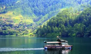 paket wisata danau toba: Perahu wisata di Danau Toba dengan latar perbukitan hijau.