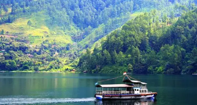 paket wisata danau toba: Perahu wisata di Danau Toba dengan latar perbukitan hijau.